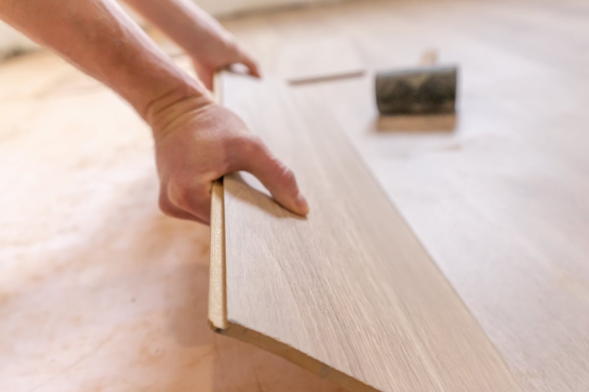 A specialist installing premium flooring planks during a residential property maintenance project